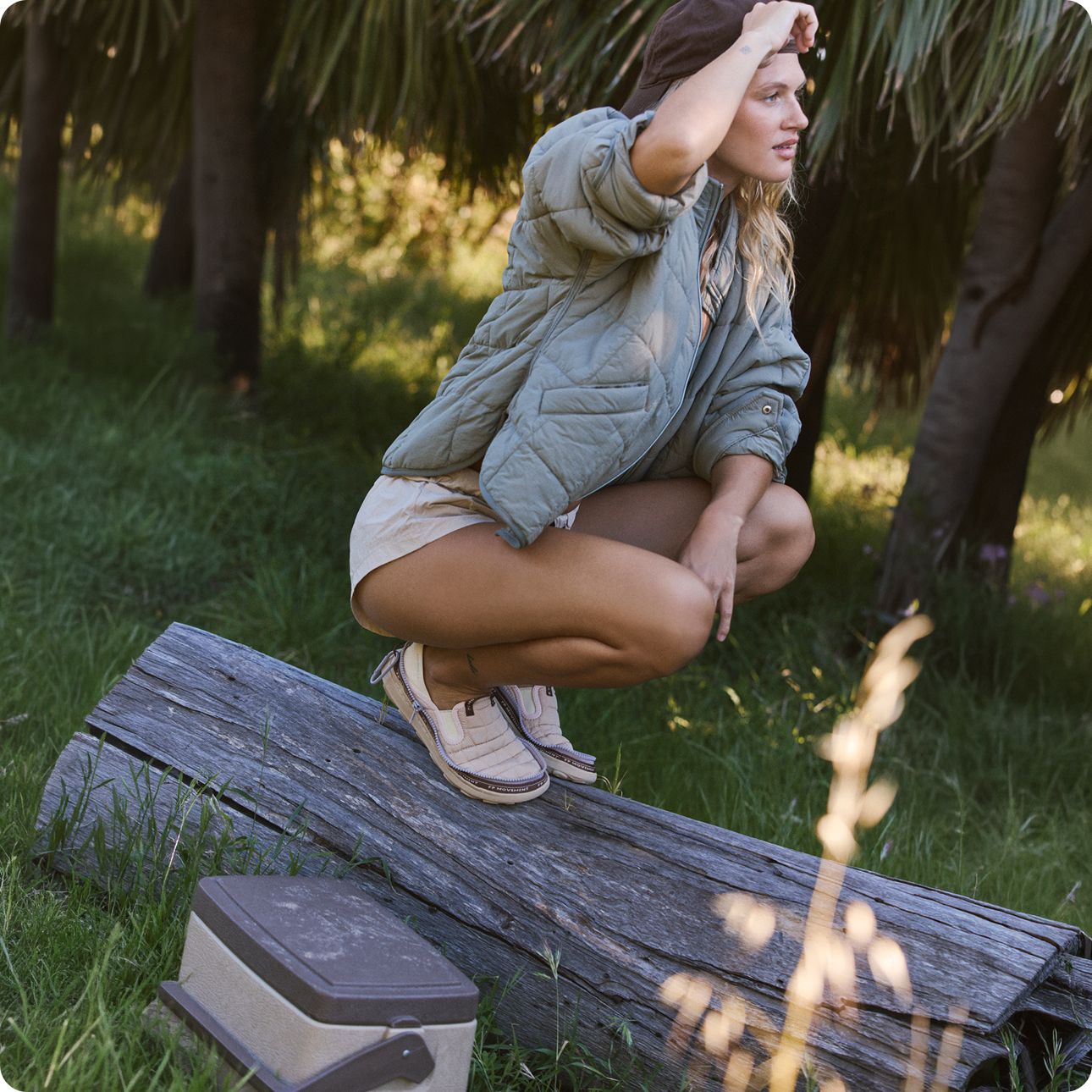 A person balancing on a fallen log gazing into the distance